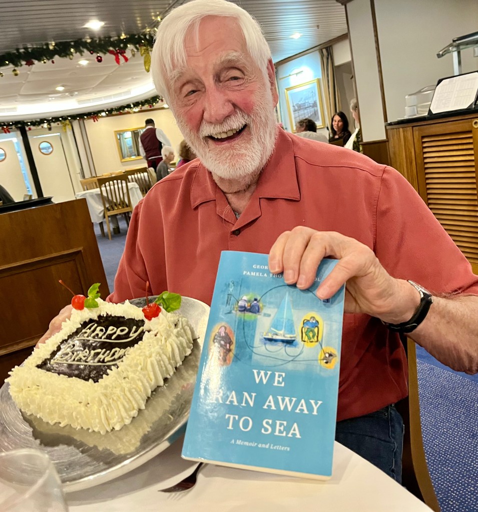 Kent with a birthday cake and a copy of We Ran Away to Sea.
